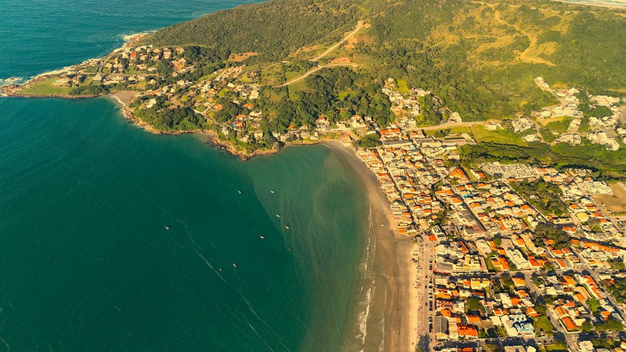 an aerial view of a beach with buildings and trees Imobiliária em Garopaba, Construtora em Garopaba